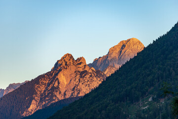 Fototapeta na wymiar Mountain Range and the peak of the Mount Mangart (2677 m.) at sunset, seen from the small village of Camporosso, Julian Alps, Tarvisio, Udine, Friuli Venezia Giulia, Italy Slovenia border, Europe.