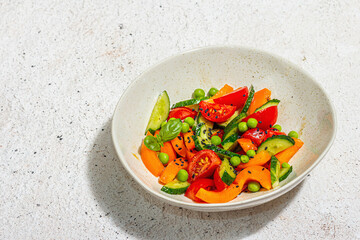 Summer vegetables salad in a modern bowl. Bright vegan food, trendy hard light, dark shadow