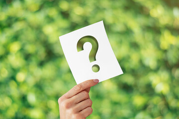 Holding note paper with Question Mark on blurred nature background. Sustainability and...