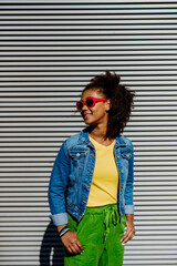Young happy multiracial teenage girl with sunglasses and afro hairstyle, standing outdoor.
