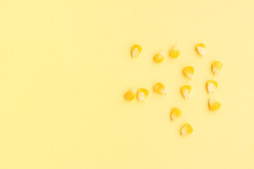 Yellow corn seeds scattered on yellow background, Top view