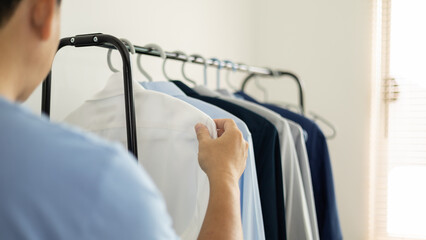 man is choosing shirt in the clothes room at home.