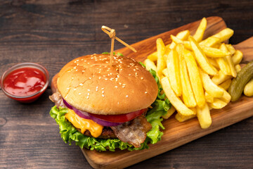 Food delivery burger hamburger with crispy bacon and potatoes fries and glass of beer on a dark background
