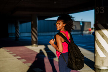 Multiracial teenage girl walking with backpack in modern city during summer day, back to school concept.