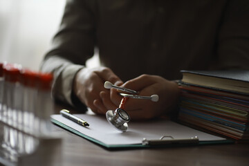 Male doctor search information in book and writtnig prescription, medical stethoscope on the desk...