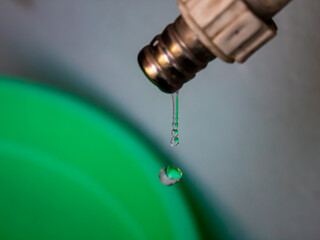 selective focus high shutter speed water droplets flowing from the tap into the bucket blurred in the background, outdoor, which can depict drought or the importance of water for the world