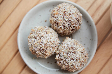 Vegan handmade gluten and sugar free delight - natural sweets balls on the wooden table close up. Healthy dessert. Raw food.