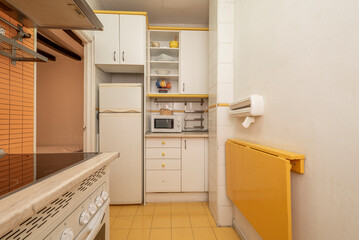 Kitchen with old white and yellow furniture, matching walls and floors