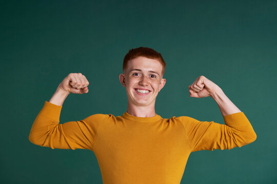 Caucasian red head  teenage boy showing his strength
