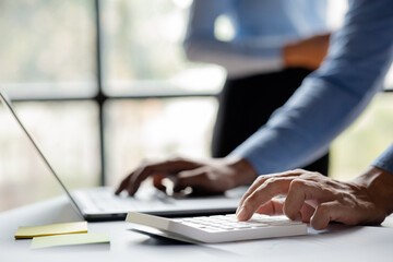 Close-up of a business man using a white calculator, a financial businessman examining the numerical data on a company financial document, he uses a calculator to verify the accuracy of numbers.