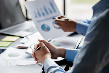 Company meeting room has businessmen and finance managers meeting together on finance topics, they are looking at information on documents and discussing together. Concept company financial management