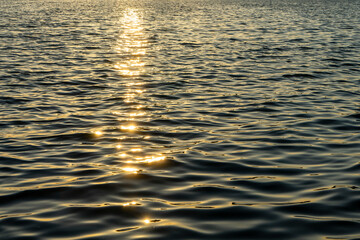 Linear golden sun glitter on rippled water surface of Aegean sea by sunset. Romantic atmosphere,...