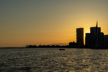 Fototapeta premium Beautiful sunset over the city in Mavişehir, a boat goes fishing, the day is ending and the sunset gives peace with its magnificent colors. Romantic sunset concept.