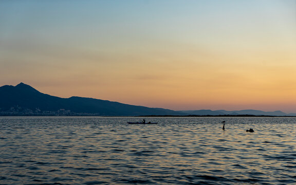 woman is kayaking at beautiful sunset on İzmir Bay, Mavisehir, Karsiyaka. Canoeing in the bay against the city of Izmir. Canoe lessons and training.Selective focus, noise effect and grainy texture. 