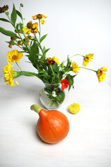 still life with orange pumpkin, yellow squash and garden flowers in vase on white background