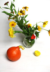 still life with orange pumpkin, yellow squash and garden flowers boquete in vase on white background