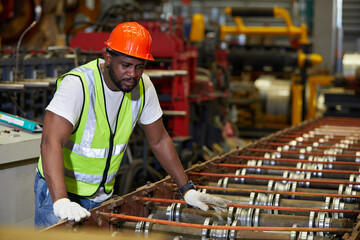 African factory worker or engineer looking at rolling machine in the metal sheet factory