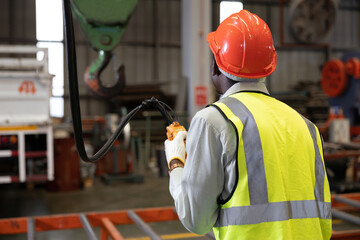 back view factory worker or engineer operating remote switch to control machine in the factory