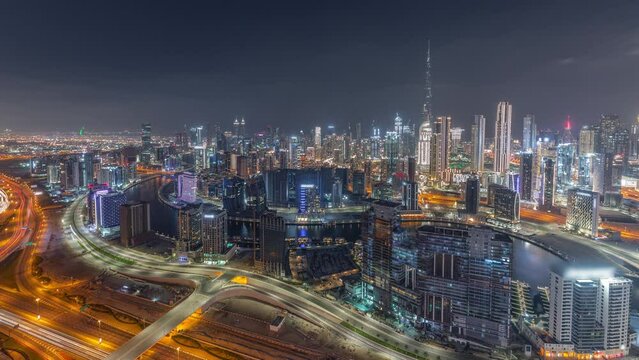 Panoramic skyline with modern architecture of Dubai business bay and downtown towers day to night transition timelapse. Aerial view with canal and construction site after sunset