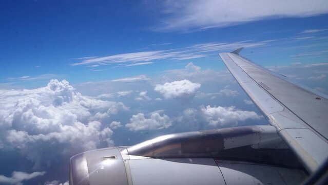 Shot of beautiful fluffy clouds and wing of airplane visible from window with the view blue sky in the background.