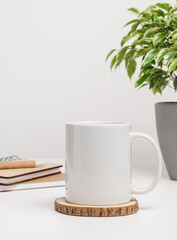 Mockup mug with notepads and houseplant at the background. Mug with copy space for logo and brand,...