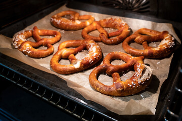Baked pretzels with the addition of coarse salt lie on a baking sheet in the oven. Traditional German food. Oktoberfest. 