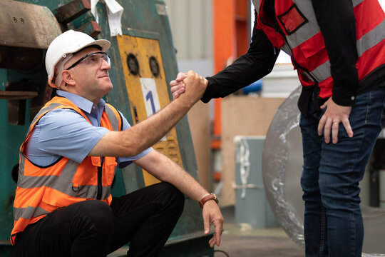 factory worker hands helping his friend to get up after a break in the factory