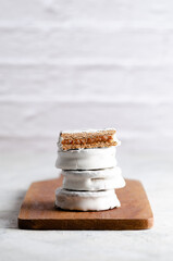 White alfajores filled with dulce de leche on a wooden board and white background. 