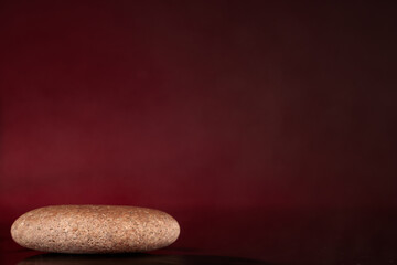 Narural stone as podium for packaging and cosmetic presentation on black, red background, copy-space.