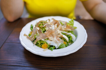at a table in a cafe in front of a girl there is a plate of dietary salad