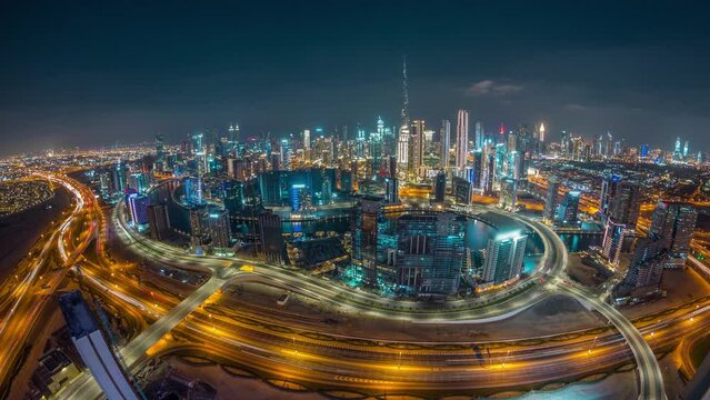 Panoramic skyline of Dubai with business bay and downtown district day to night timelapse. Aerial wide angle view of many modern skyscrapers with traffic on al khail road after sunset.