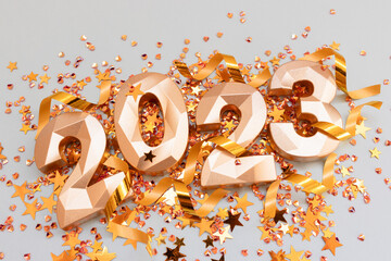 Closeup of 2023 golden numbers, stars confetti and ribbons on a blue pastel background. Creative New Year's concept.
