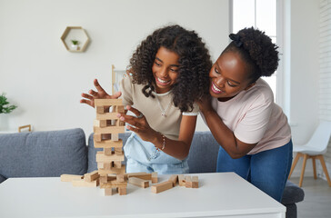 Family plays board game. Cheerful and friendly young woman and her teenage daughter are having fun...