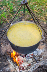 A cauldron in which kulesh is boiled hangs on a tripod over the fire