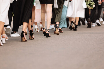 the feet of the group of people are walking outdoors. graduation day. stylish young guys and girls in stylish shoes.