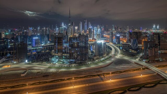 Panoramic skyline of Dubai with business bay with financial and downtown district during all night timelapse. Aerial view of many modern skyscrapers and busy traffic on al khail road. United Arab