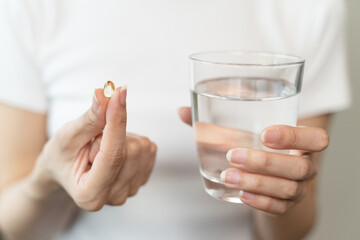 close up person pouring multivitamin capsules to her hands - obrazy, fototapety, plakaty