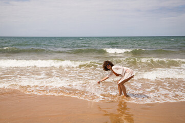 Young beautiful woman in bikini walking along the beach shore. The woman is enjoying her trip to a paradise beach while making different gestures and expressions. Holidays and travels.