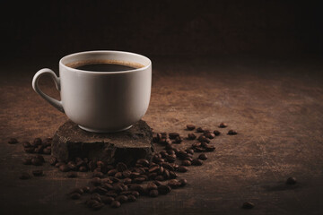 Cup of freshly brewed roasted coffee beans on brown background