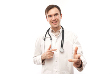 Portrait of friendly positive young male doctor in white medical coat chooses you, points finger at camera isolated on white background.