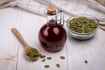 Pumpkin seed oil in a glass vessel and pumpkin seeds close-up, space for copying and selective focus on a bottle of brown liquid