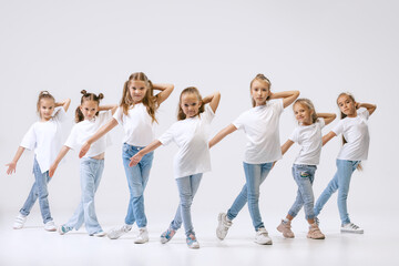 Active little girls, sportive kids in casual style clothes in motion isolated on white studio...