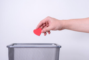 Handmade wooden heart tossed in the trash for recycling and disposal.