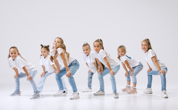 Portrait Of Happy, Active Little Girls, Sportive Kids In Casual Clothes Dancing Isolated On White Studio Background. Concept Of Music, Fashion, Art, Childhood, Hobby