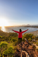 Obraz premium Adventurous Woman Hiker overlooking Sandy Beach on the West Coast of Pacific Ocean. Canadian Nature Landscape Background. Cox Bay Lookout, Tofino, Vancouver Island, BC, Canada.