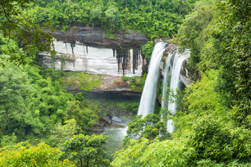 Fototapeta premium Waterfall in the deep forest. Huai Luang waterfall Huai Luang waterfall middle of the humid forest at Ubon Ratchathani, Thailand, Asia. Leaf moving low-speed shutter blur.