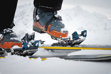 Close-up of the legs of an athlete-skier in ski boots against the backdrop of snow-capped...
