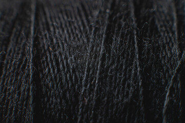 Extremely close-up macro of the surface of a spool of thread in black. Low key. Selective focus. macro shot