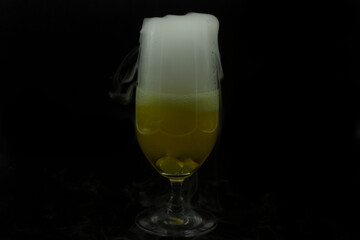 Bubbles foam and white smoke by cooling dry ice from beer contained in glass fancy drink for Halloween party