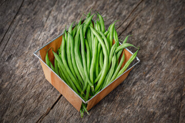 Organically homegrown French filet green beans, 'Maxibel' variety, in a quart container on a rustic vintage wooden background - obrazy, fototapety, plakaty